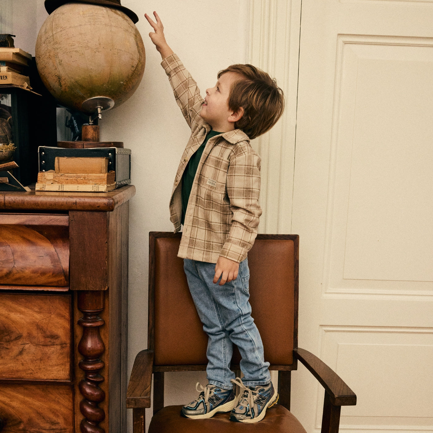 Jongen ontdekt een vintage interieur in een geruit overshirt en lichtblauwe jeans uit de Daily7 Kids collectie.